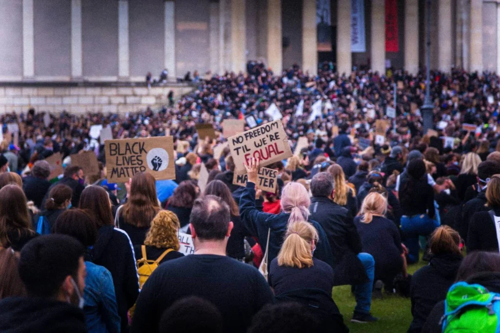 Large crowd gathered at a public protest holding signs advocating for equality and civil rights.