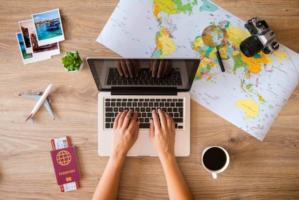 Traveler planning a solo trip on a laptop with a world map, passport, and coffee on a desk.