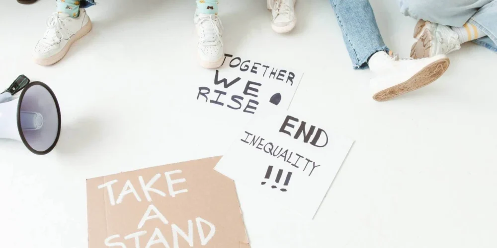 Megaphone and protest signs on the ground with messages about inequality and taking a stand.
