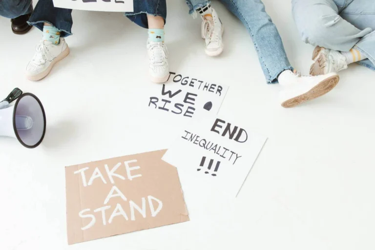 Megaphone and protest signs on the ground with messages about inequality and taking a stand.