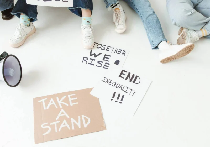 Megaphone and protest signs on the ground with messages about inequality and taking a stand.