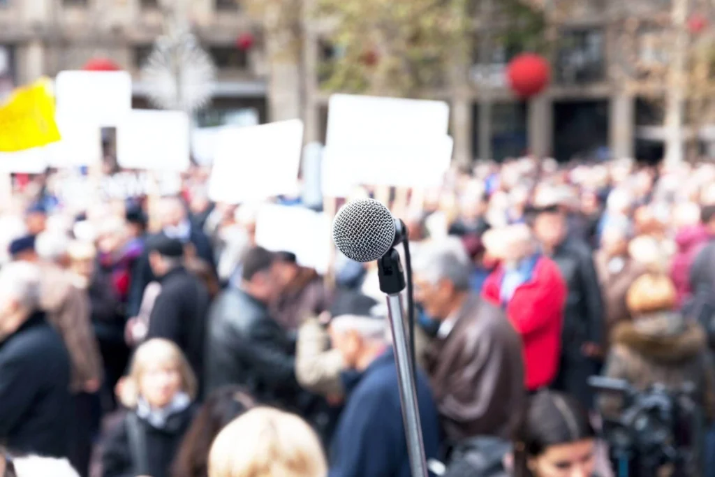 Microphone positioned in front of a large crowd during a public event or gathering.