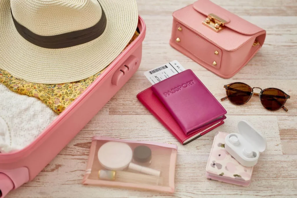 Packed pink suitcase with passport, boarding pass, accessories, and travel essentials for a solo trip.
