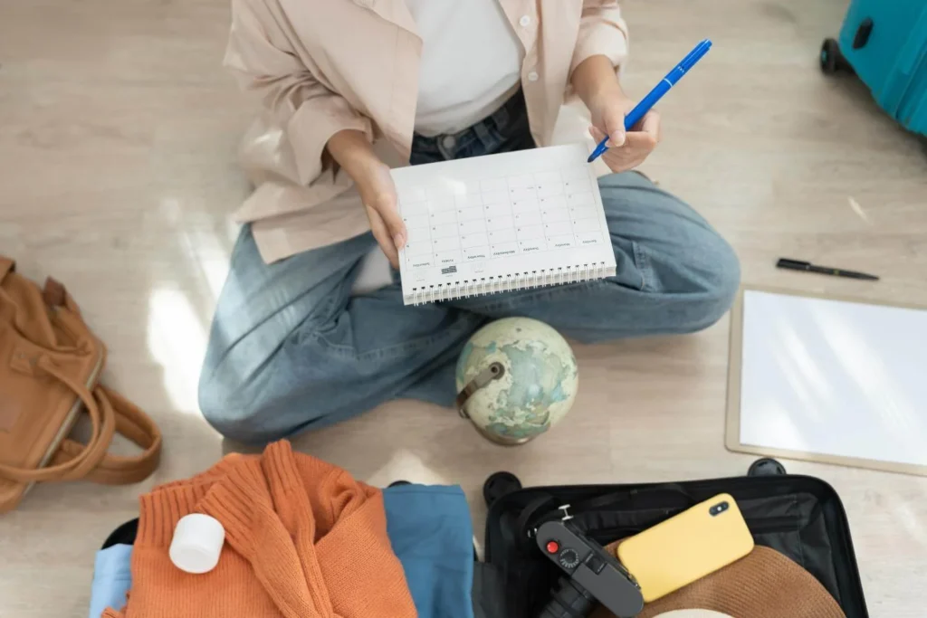 Traveler planning a solo trip with a calendar, globe, and open suitcase on the floor.
