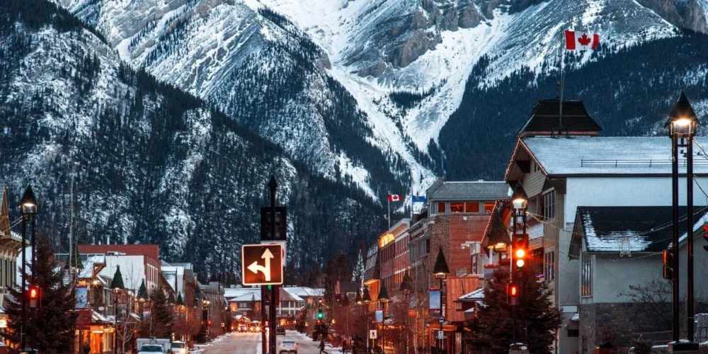 Winter street scene in Banff, Canada with snow-covered mountains and town lights, showing what winter travel in Canada looks like for solo travelers.