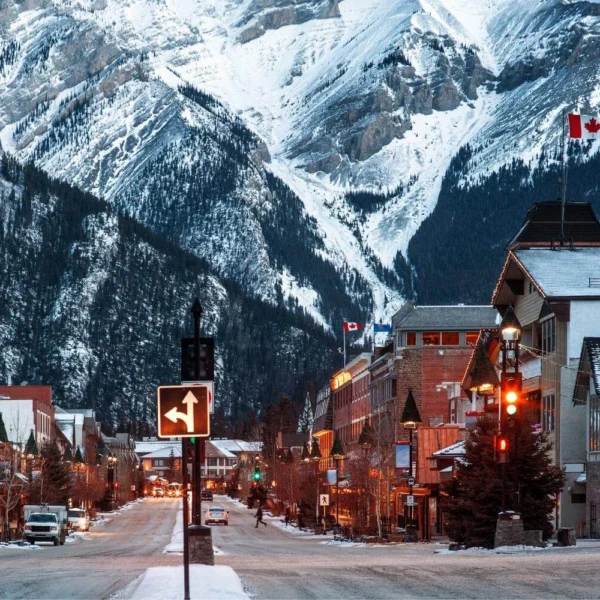 Winter street scene in Banff, Canada with snow-covered mountains and town lights, showing what winter travel in Canada looks like for solo travelers.