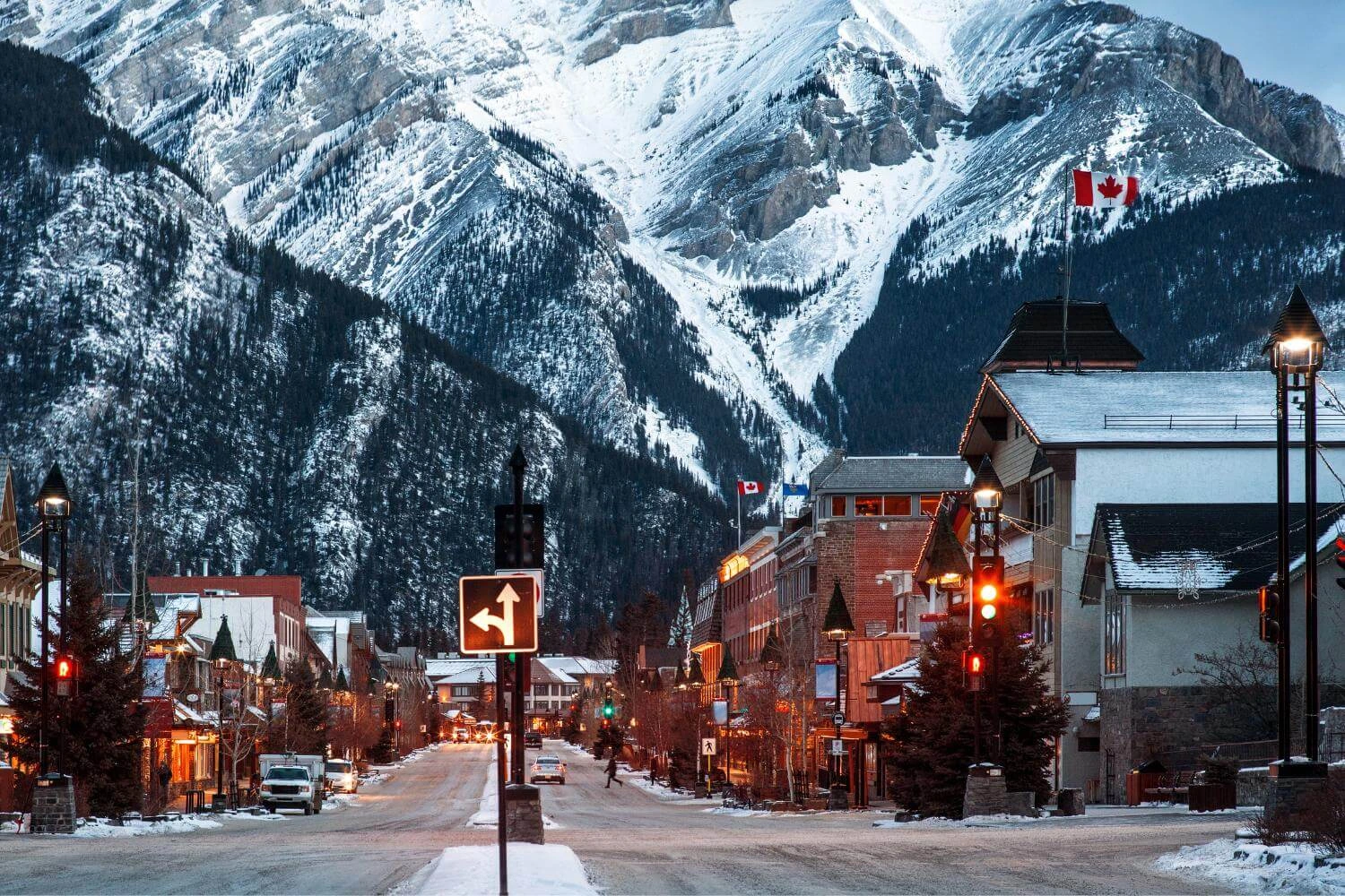 Winter street scene in Banff, Canada with snow-covered mountains and town lights, showing what winter travel in Canada looks like for solo travelers.