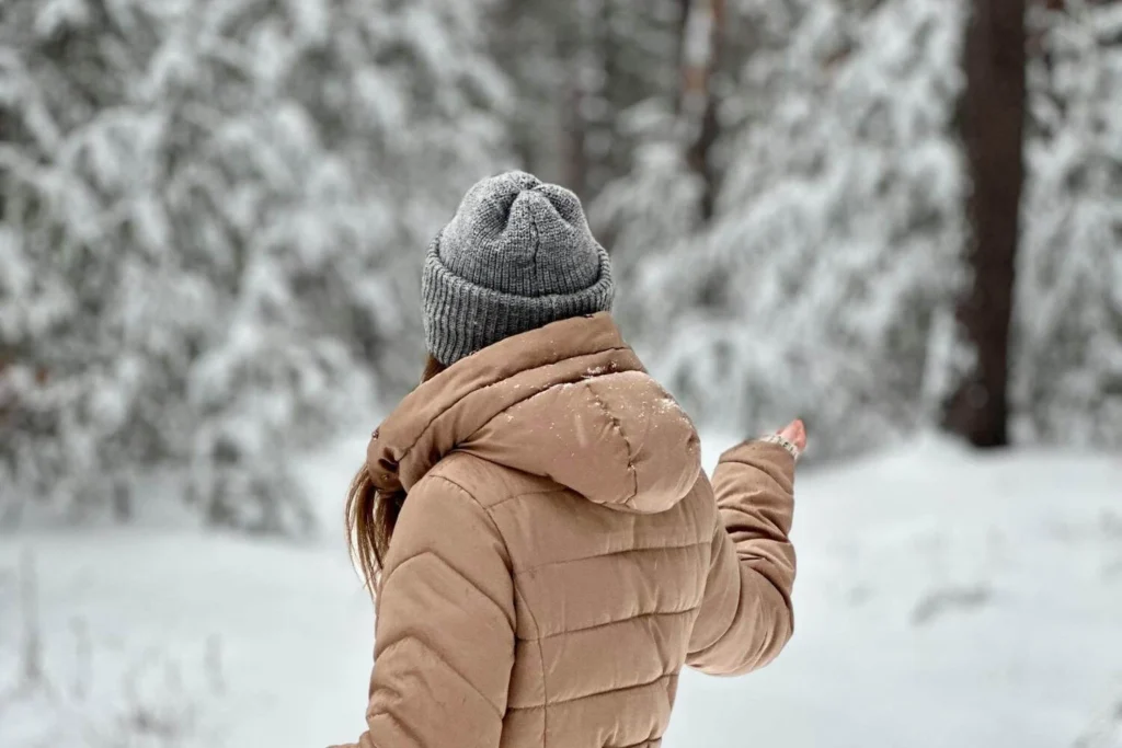 Solo traveler walking alone through a snowy forest during winter, reflecting and finding calm outdoors.